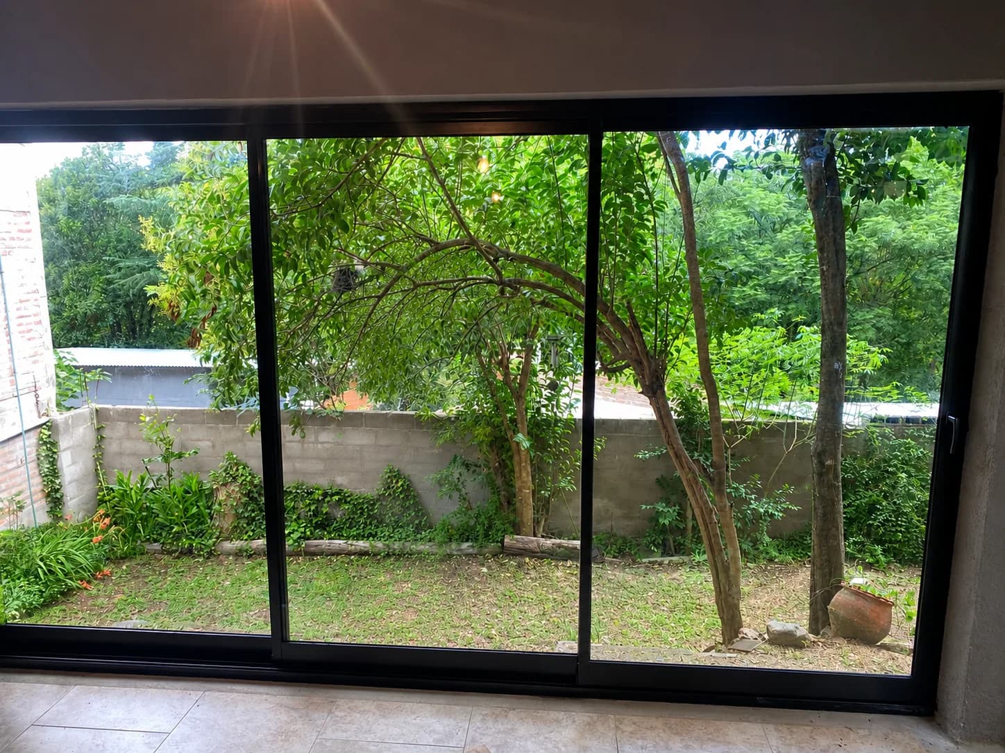 Corrediza de tres hojas en aluminio negro con vista al jardín