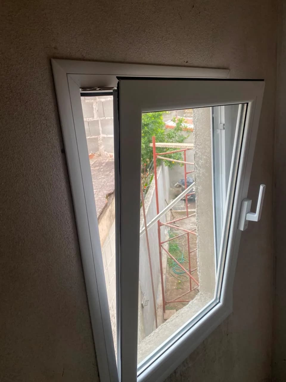 Ventana oscilobatiente de aluminio blanco abierta en posición de ventilación